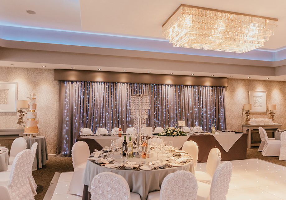 Fairy light curtain behind top table with white decor